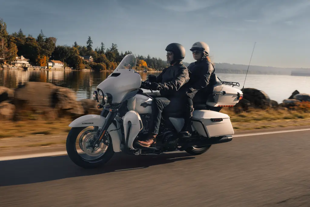 2024 Harley-Davidson Ultra Limited, white, ridden two-up along a lakeside road with the Tour-Pak and fairing lowers in view