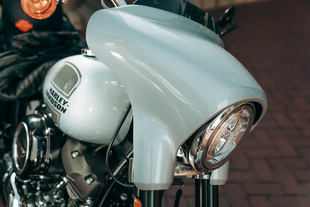 Close-up of the mini-fairing, short black screen and round headlamp on a 2023 Harley-Davidson Sport Glide FLSB.